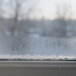 Skroplona woda i zaparowana dolna część szyby okna PCV zimą